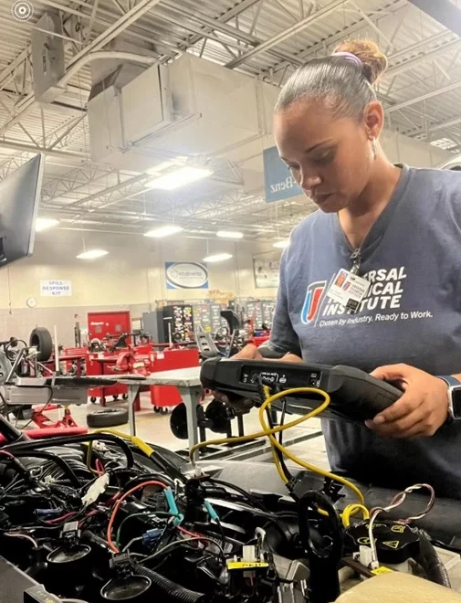 Jinelee Galindez examining an engine while studying for her tech career.